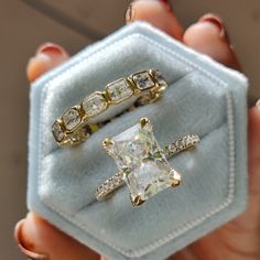 two gold rings with white and yellow diamonds on them in a blue velvet ring box