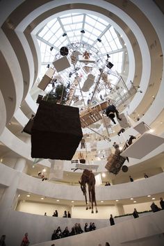 people are standing in the middle of a large room with an animal sculpture hanging from it's ceiling