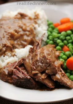 a white plate topped with meat and rice covered in gravy next to green peas