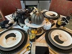 the table is set with black and white plates, pumpkins, and other decorations