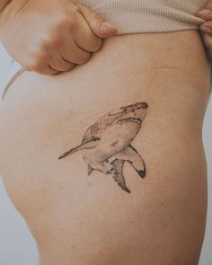 a woman's stomach with a tattoo of a shark on the back of her belly