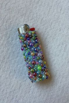 a cell phone covered in lots of beads on top of a white surface with a red clip