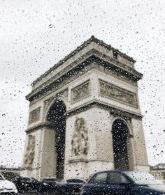 rain is falling on the window and cars are parked in front of a building with a clock tower