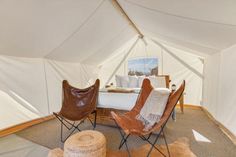 the inside of a tent with two chairs and a bed