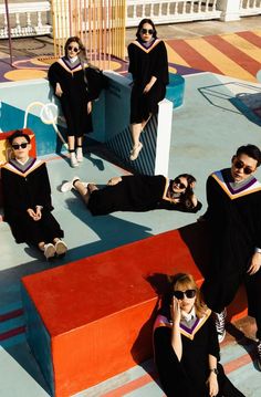 a group of people dressed in graduation gowns and sunglasses posing for a photo together