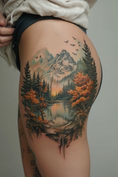 a woman's thigh with an image of mountains and trees painted on the side