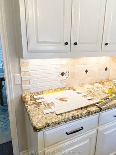 the kitchen counter is being remodeled with white cabinets and marble work on it's backsplash