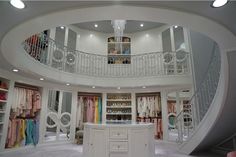 the inside of a large closet with lots of clothes on shelves and drawers in it