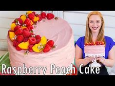 a woman holding a cake with raspberry peach icing