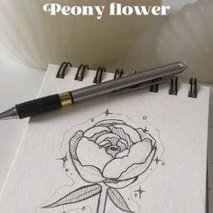 a pen sitting on top of a piece of paper next to a drawing of a flower