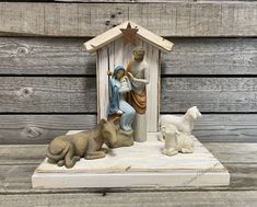 a nativity scene with figurines in front of a wooden wall and wood planks