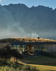 a house with grass on the roof and mountains in the background