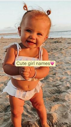 a baby is standing on the beach with an emersonon sign in front of her