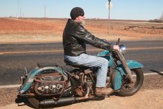 a man riding on the back of a blue motorcycle