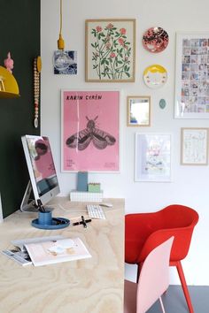 a desk with a chair, computer and pictures on the wall