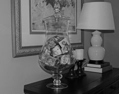 a glass vase filled with pictures on top of a wooden table next to a lamp