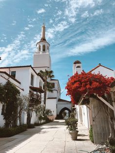 a white building with a steeple and red flowers