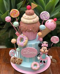 a mickey mouse figurine sitting on top of a cupcake with candy and lollipops