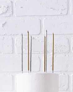 three needles sticking out of a cake with white frosting and gold piping on top