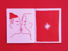 an open book with a drawing of two people kissing in front of a red background