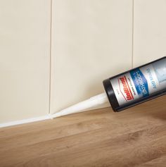 a close up of a can of cleaner on a wooden floor next to a tile wall