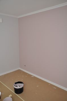 an empty room with a bucket on the floor and paint rollers in front of it