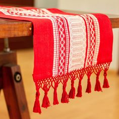 a red and white table runner with tassels hanging from it's sides