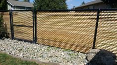 a fence that has rocks in front of it and grass on the ground next to it