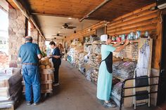 a woman in a long blue dress is standing near a store with shelves full of food