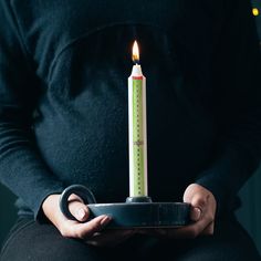 a person holding a plate with a lit candle in it's middle and a measuring tape on top