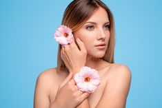 a beautiful young woman holding pink flowers in her hands