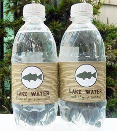 two plastic water bottles with fish labels on them sitting on a table next to some plants