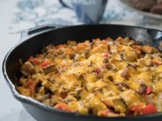 a casserole dish with meat and cheese in it on a table next to bread