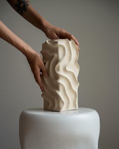 a person is decorating a cake with white frosting and waves on the top