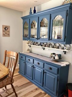 a kitchen with blue cabinets and wooden floors in it's center area, along with a dining room table