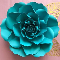 a large blue flower sitting on top of a pink table next to a gold doily