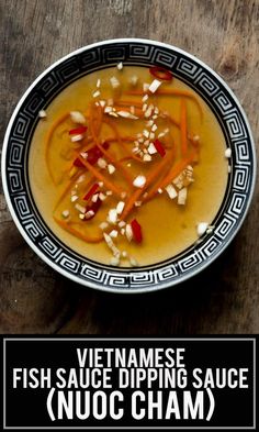 a bowl filled with fish sauce on top of a wooden table