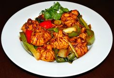 a white plate topped with chicken and veggies on top of a wooden table