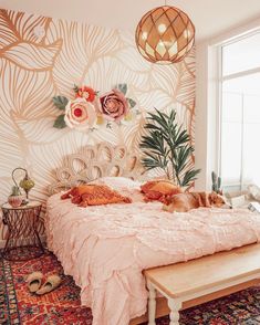 a cat laying on top of a bed in a room with floral wallpaper and rugs