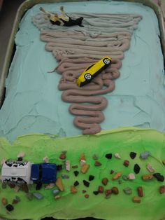 a birthday cake with cars and rocks in the shape of a tornado on it's side