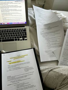 several papers are on the bed next to a laptop