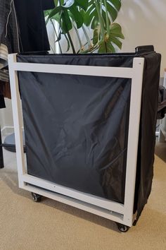 a television sitting on top of a cart next to a plant in a potted planter