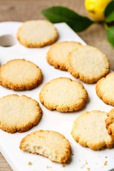 a white tray filled with cookies on top of a wooden table next to lemons