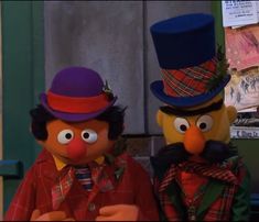 two characters dressed in costumes standing next to each other with hats on their heads and one wearing a top hat