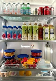 an open refrigerator filled with lots of different types of drinks and fruit in bowls on the shelves