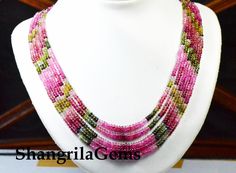 a white mannequin with pink and green beaded necklaces on it's neck