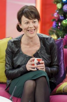 a woman sitting on top of a pink couch holding a coffee cup in her hand