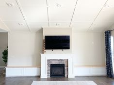 an empty living room with a fireplace and flat screen tv mounted above the fire place