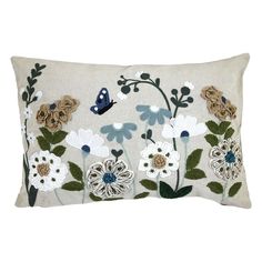 an embroidered pillow with white and blue flowers on the front, and a butterfly flying over it