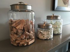 a glass jar filled with wooden blocks on top of a counter next to a canister